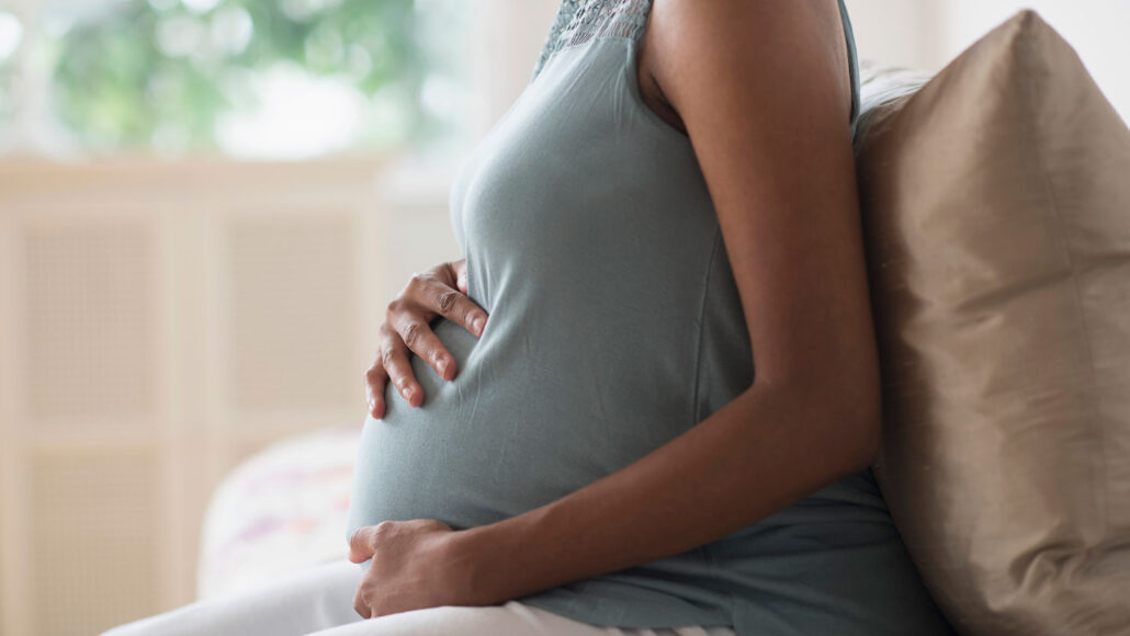 An image of a pregnant woman's torso sitting on a couch.