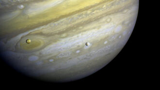 A photo of Jupiter with its moons Io and Europa seen in front.