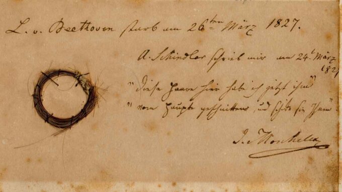 image of a circular lock of Beethoven's hair attached to an old piece of paper with something written in cursive script