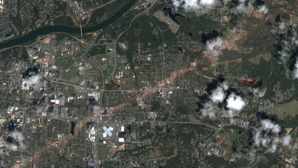 A satellite view of Tuscaloosa, Alabama, with a clear tornado track carving through the city