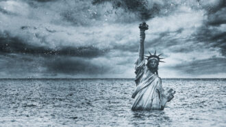 The Statue of Liberty up to its waist in water, under gray cloudy skies