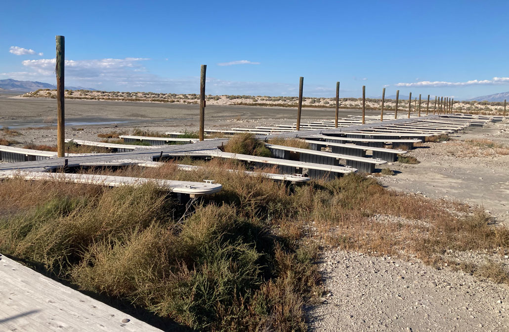 A photo of several wooden docking slips sitting on top of vegetation on dry ground instead of resting in water.