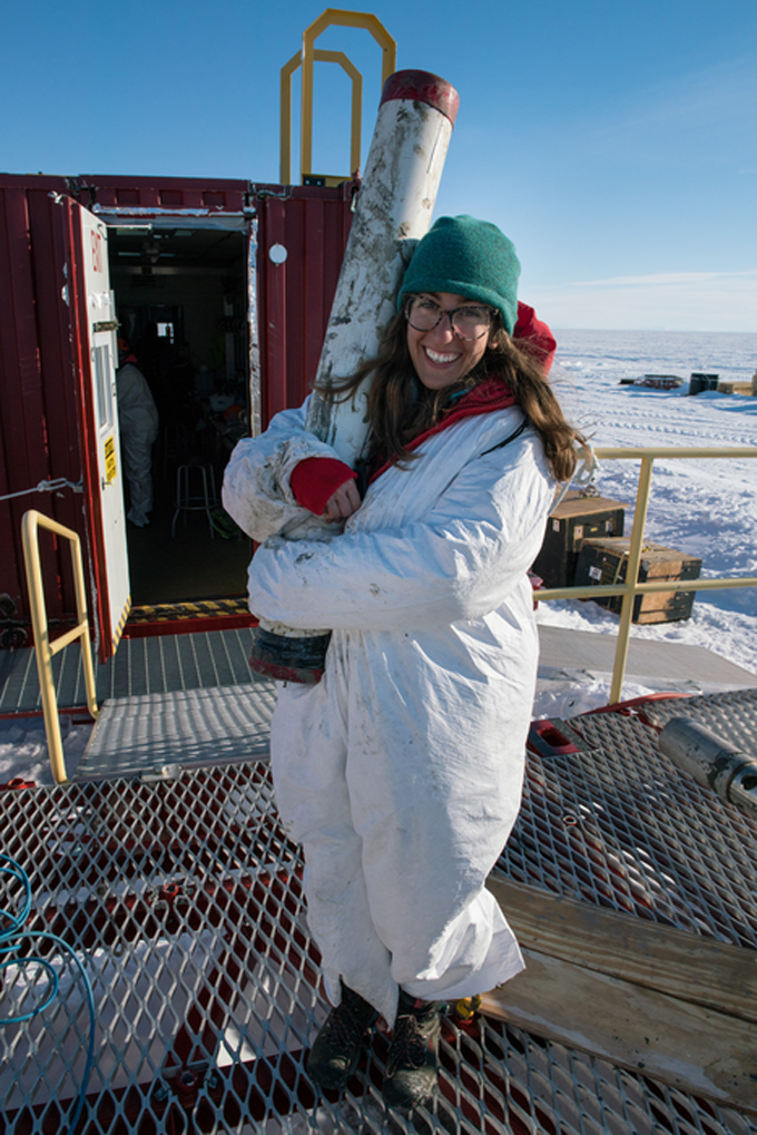 A photo of Ryan Venturelli holding a tall tube of sediment to her chest.