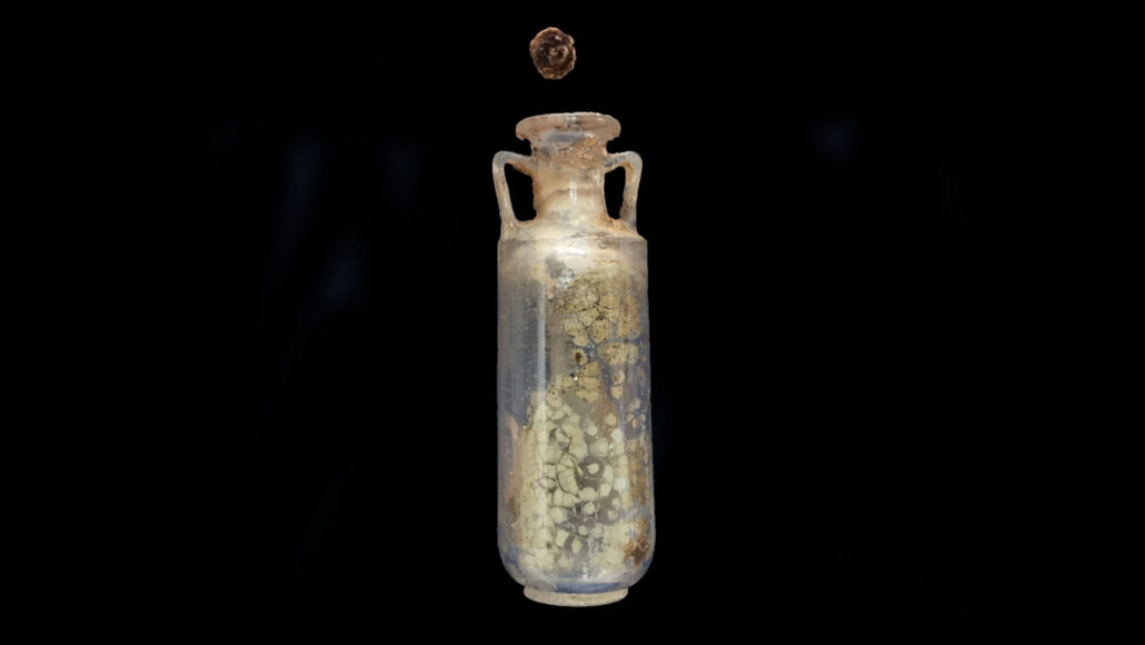 An ancient quartz bottle with handles on either side against a black backdrop