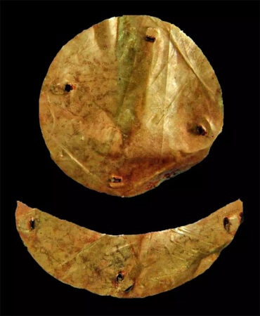 A photo of a gold metal circle and a gold metal crescent moon on a black background. Both were found in a Xiongnu tomb.