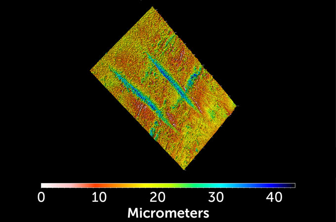 An image of a 3-D model of the deepest marks on a hominid fossil leg bone in micrometers is shown in blue and green.