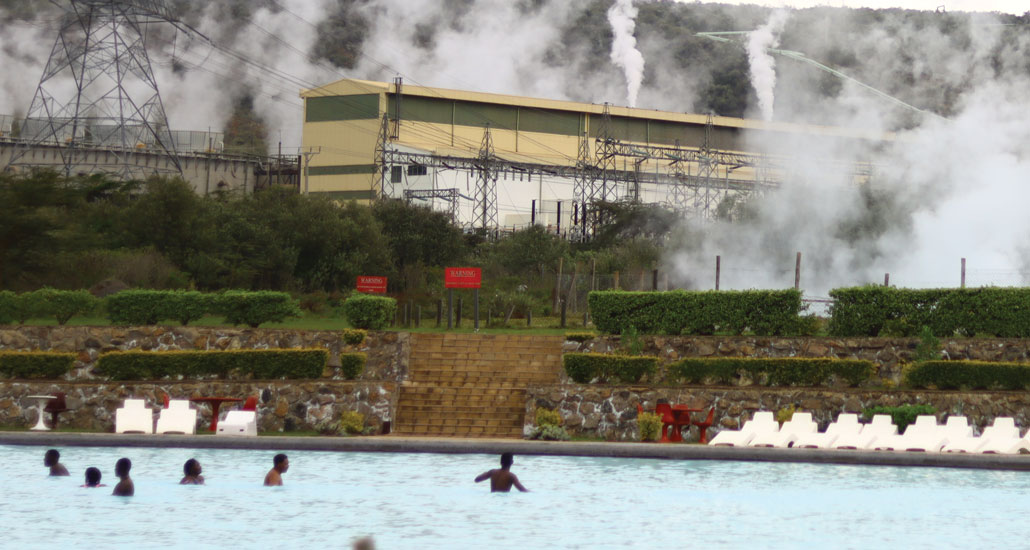 people in a spa pool with steam rising in the background near the Olkaria geothermal power project