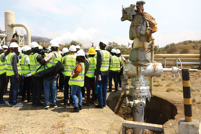 photo of a group of a people in yellow vests and hard hats standing next to a well in Olkaria