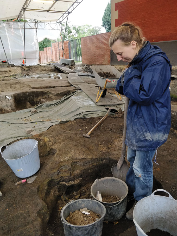 photo of Bente Philippsen in an excavated area surrounded by buckets of material