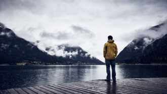 detecting fake news assignment vaccines answers A photo of a man in a yellow raincoat standing at the end of a dock with his back to the camera. The background, in black and white, shows Lake Achen in Austria.