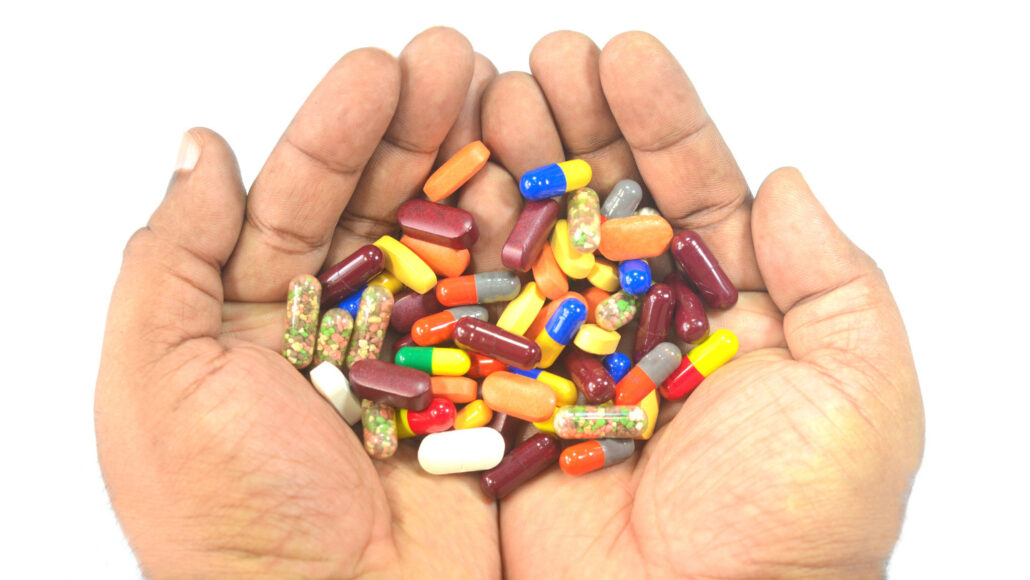 A photo of a person's hands cupped around a pile of multicolored pills.