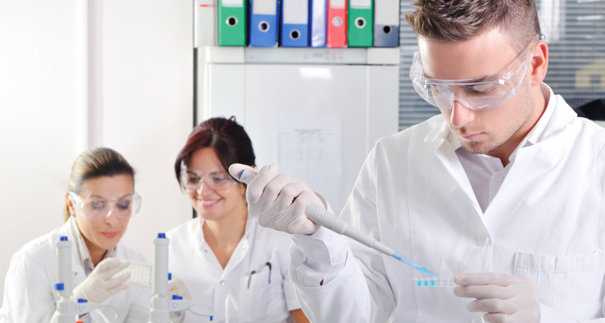 male scientist in foreground, two women scientists in background