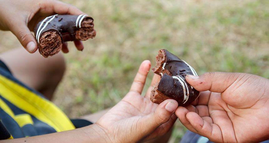child handing another child a donut