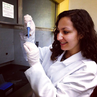 A photo of Elizabeth Atkinson, an evologuionary and population geneticist, working in a lab.