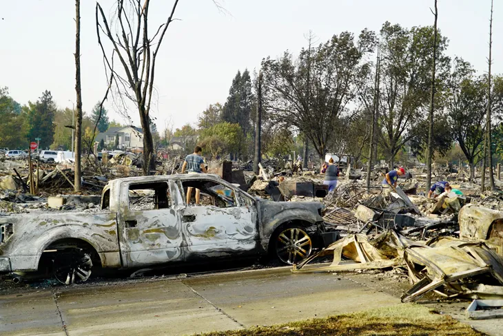 a photo of the damage from the Tubbs Fire including a burned out white pickup truck and debris from demolished homes