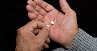 person holding aspirin tablets