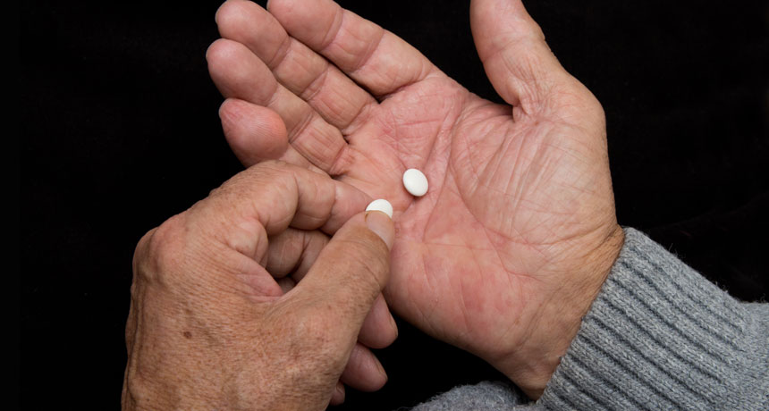 person holding aspirin tablets