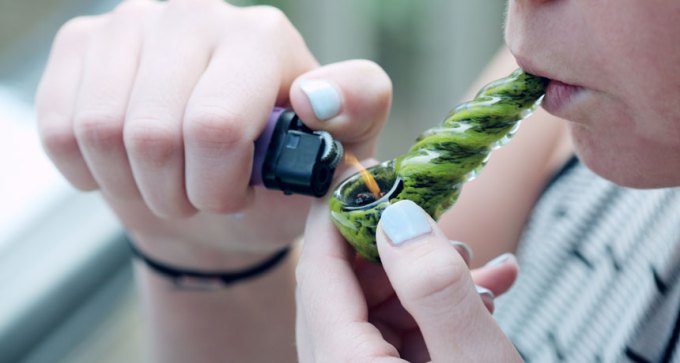 person lighting marijuana pipe