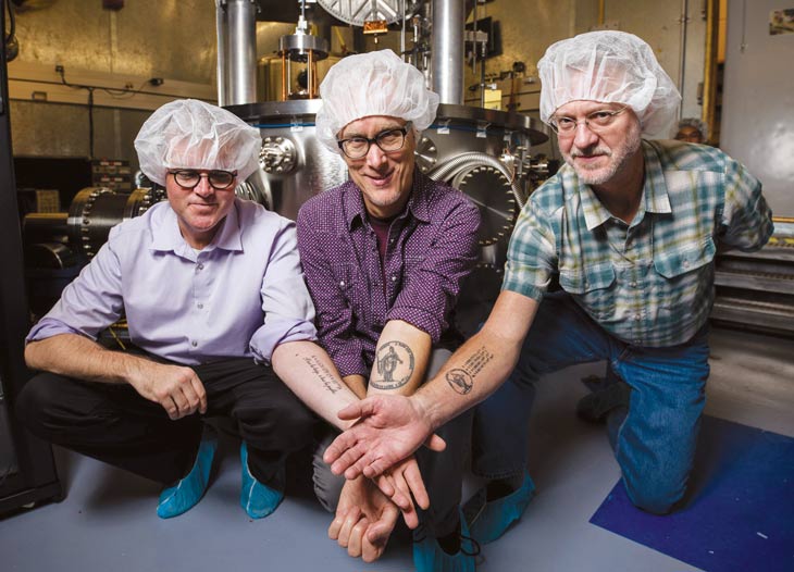 three scientists showing their forearm tattoos, of the Planck constant