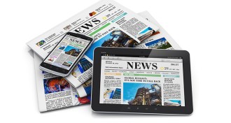 a pile of newspapers and a table and a phone showing news