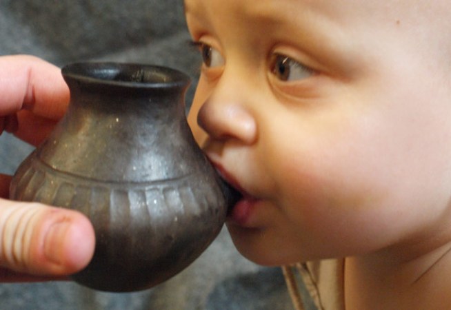 Baby tries out replica ancient baby bottle