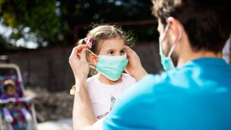 Parent putting mask on child