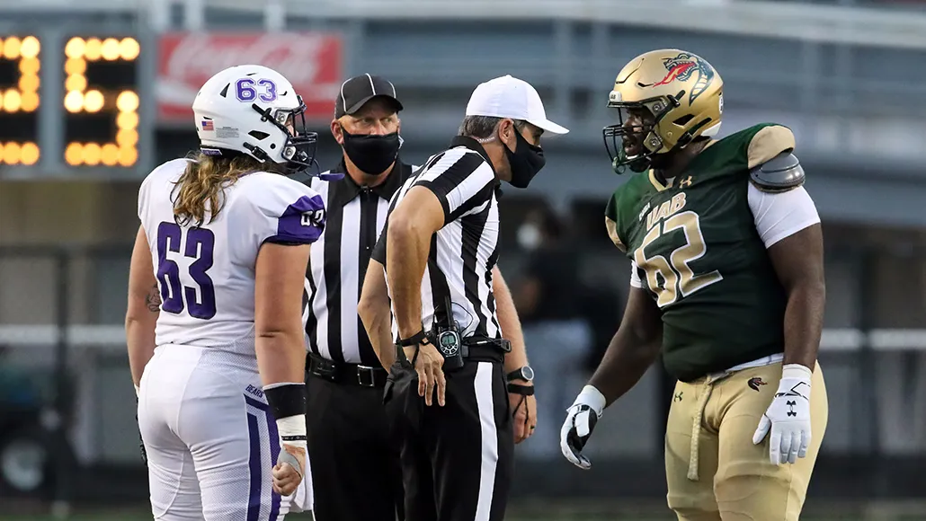 college football players talking to masked referees