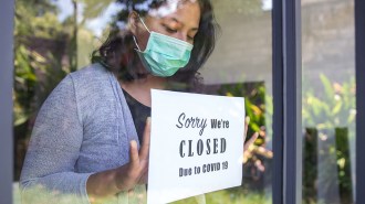 woman putting a closed sign in a window