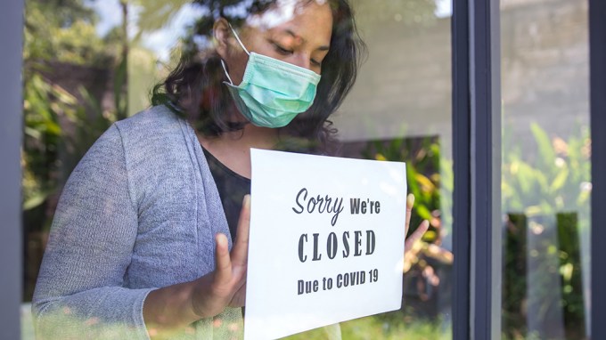 woman putting a closed sign in a window