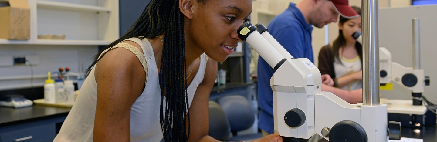 A Black student looking into a microscope