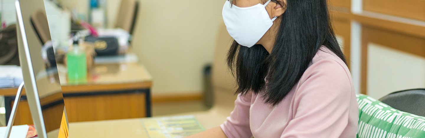 masked student looking at a computer