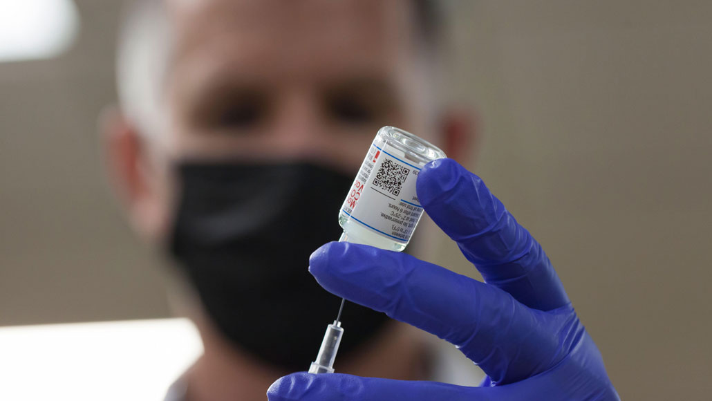 a person fills a needle with COVID-19 vaccine