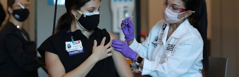a woman receives her first dose of the COVID-19 vaccine at a hospital