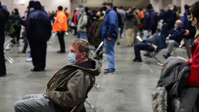 image of people siting and standing in line to get doses of the COVID-19 vaccine