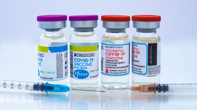 photo of four glass bottles of vaccine with two syringes sitting in front of them