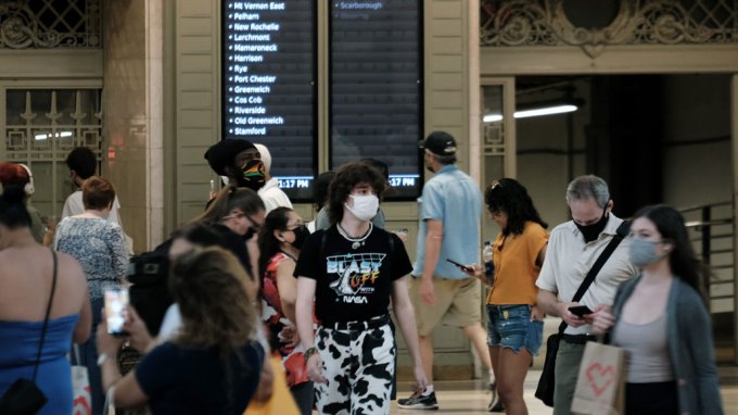 a crowd of people wearing face masks in Grand Central Station in New York City