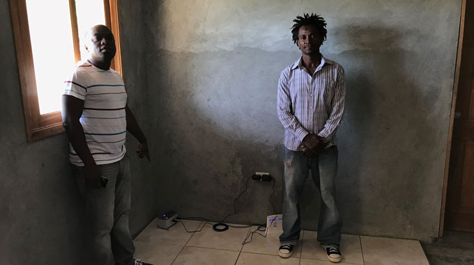 Steeve Symithe and Pier-Guild Mezile stand in a room with a small seismometer
