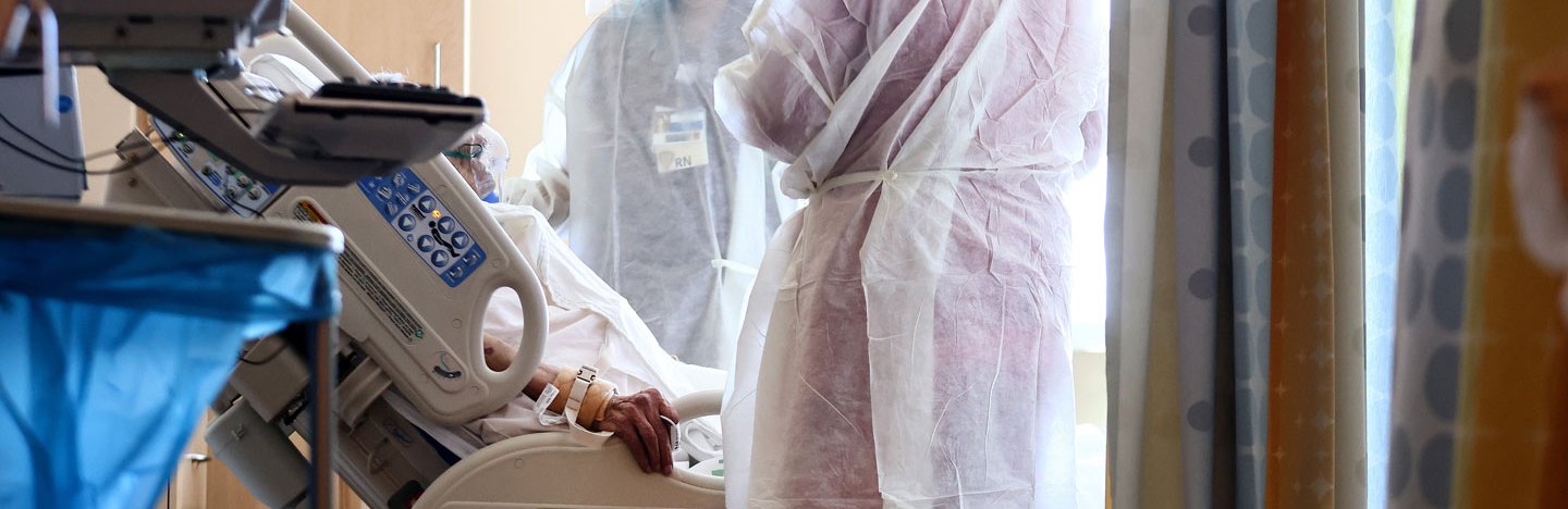 doctors tend to a COVID-19 patient in a hospital bed