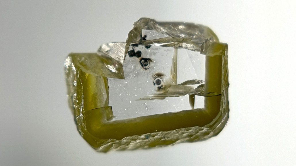 a slice of diamond with tiny gray blobs of a newfound mineral called davemaoite