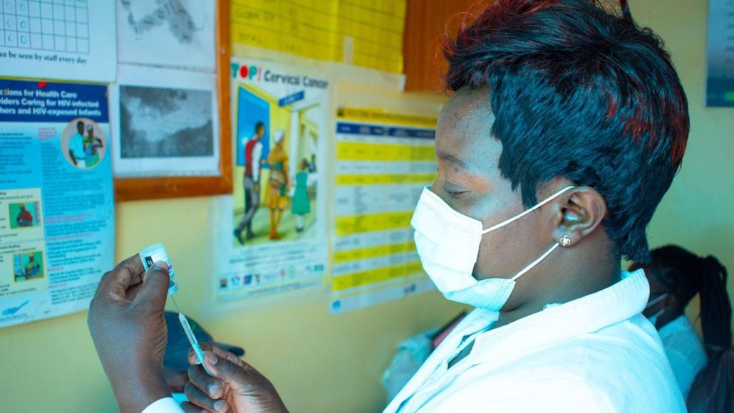 a nurse draws up a syringe from a vial of COVID-19 vaccine