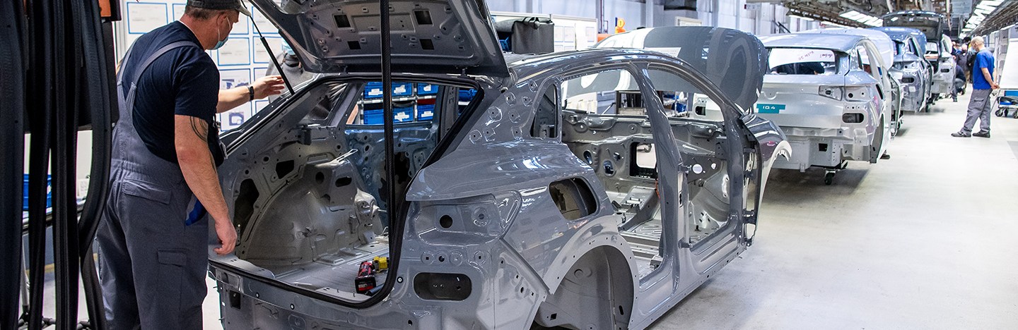a photo of workers in an automobile factory working on electric vehicles