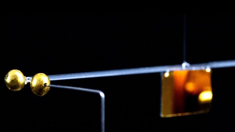 a horizontal glass beam with gold spheres