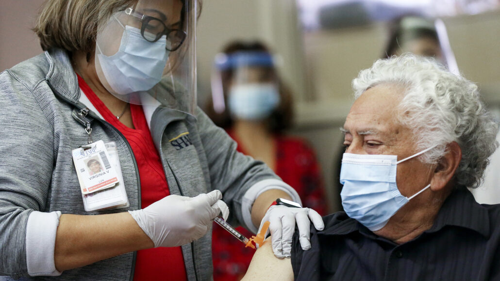 person injecting a COVID-19 vaccine into someone's arm