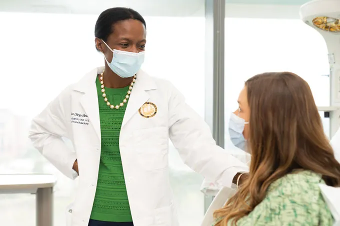 Cynthia Gyamfi-Bannerman stands next to a seated patient