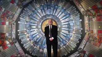 Peter Higgs in front of a photo of a detector at the Large Hadron Collider