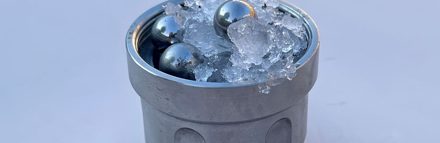 A metal vessel filled with ice and stainless steel balls