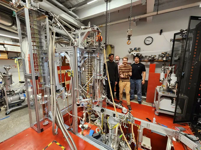 A team of physicists stand behind their experimental apparatus which captured a single electron in a trap.