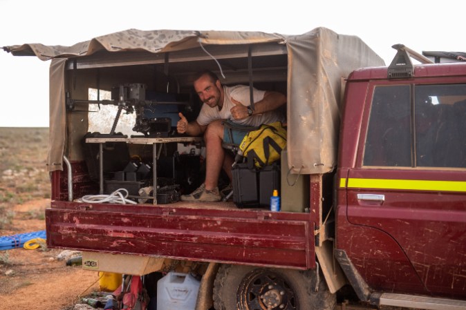 Meteorite hunter Seamus Anderson sits in the back of a truck on his drone-based expedition in Western Australia in 2021.
