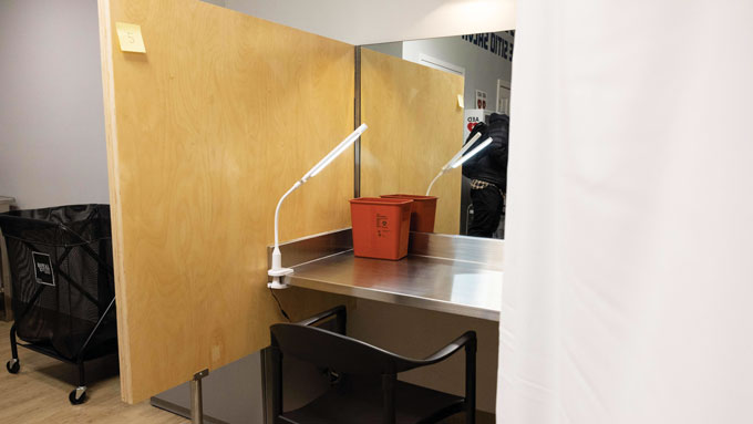 Drug consumption booth with a brown wall, chair and light.