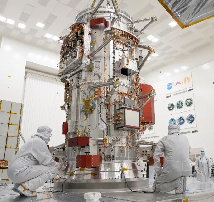 An image showing people in white lab suits crouched around the assembled core of NASA's Europa Clipper spacecraft.